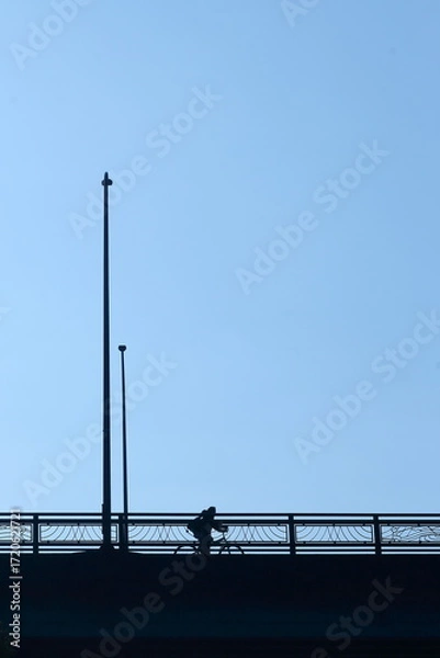 Fototapeta 青空を見上げながら陸橋を自転車で渡る人
