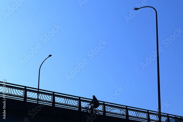 Fototapeta 青空を見上げながら陸橋を自転車で渡る人
