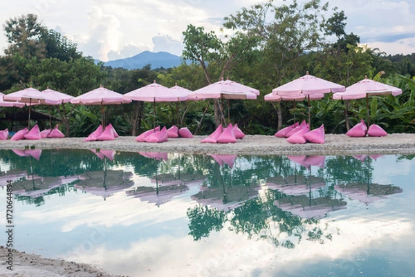 Fototapeta Pink umbrellas on the artificial sea behind are beautiful green mountains