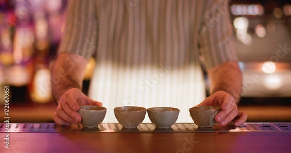Fototapeta Barman work. Pub process. Bartender preparing row of little clay bowls for traditional oriental beverage. Ceramic dishes for sake.