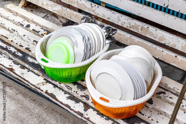 Fototapeta Colorful bowls with stacked plates on weathered wooden bench