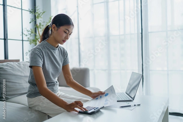 Fototapeta Asian women using calculator calculating Monthly expenses
And Working With Laptop at home