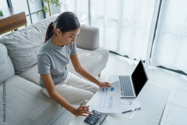 Fototapeta Asian women using calculator calculating Monthly expenses
And Working With Laptop at home