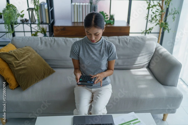 Fototapeta Asian women using calculator calculating Monthly expenses
And Working With Laptop at home