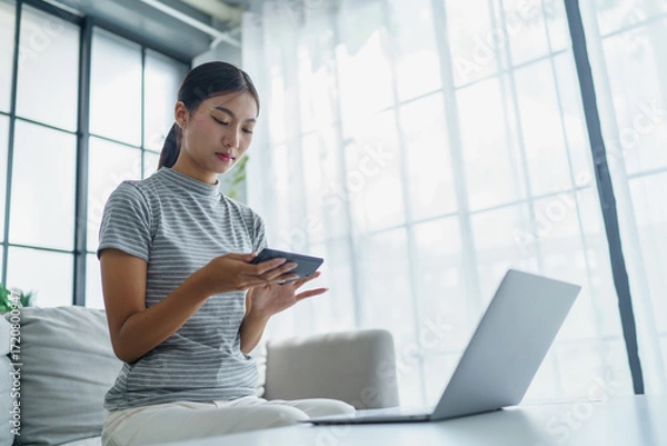 Fototapeta Asian women using calculator calculating Monthly expenses
And Working With Laptop at home
