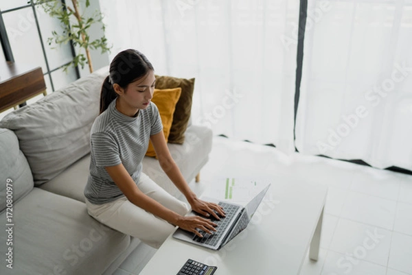 Fototapeta concentrated Asian woman using laptop computer creative girl working and typing on keyboard.