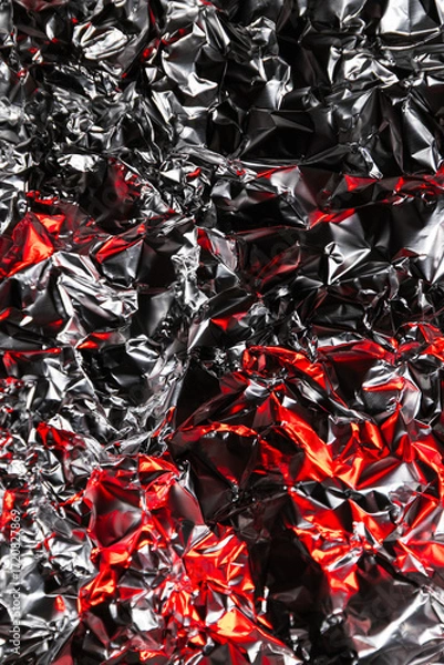 Fototapeta Shiny crumpled foil with silver and red reflections creating a metallic abstract design. Futuristic texture with chrome surface and cyberpunk background style