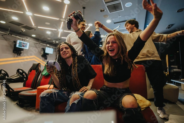 Fototapeta Group of enthusiastic friends playing video games in a vibrant gaming lounge, celebrating their victory with joy and excitement. A scene showcasing fun, technology, and strong social connections.