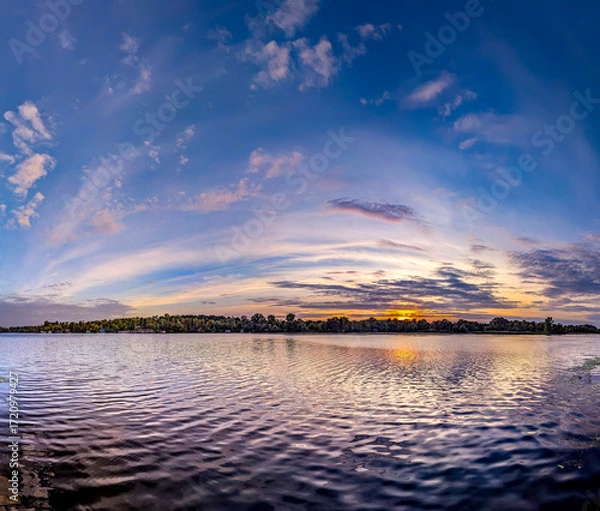 Fototapeta A panoramic dome of cirrus clouds. An arch of magical purple sunset with yellow and orange reflections from the sun is reflected calm waves river. A calming evening spectacle. Pink flakes of steam.