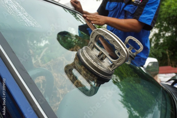 Fototapeta Glazier using tools repairing to fix crack broken windshield, windscreen on the front window glass of the machine car accident.