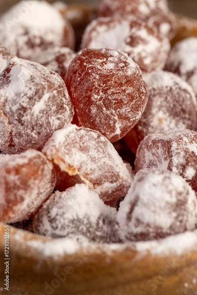Fototapeta dried kumquat and powdered white sugar in a wooden bowl, dried orange kumquat fruits are placed in a wooden bowl and sprinkled with powdered white beet sugar