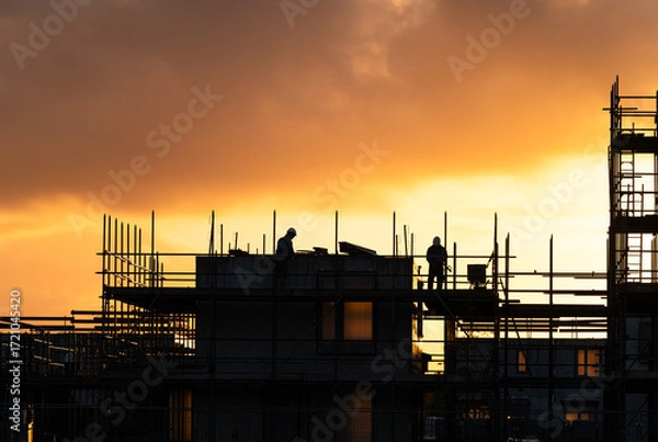Fototapeta Construction workers working on a housing project in the Netherlands during a tranquil sunrise.

