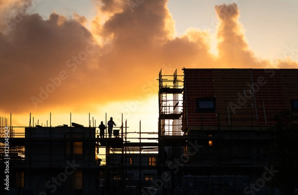 Fototapeta Construction workers working on a housing project in the Netherlands during a tranquil sunrise.

