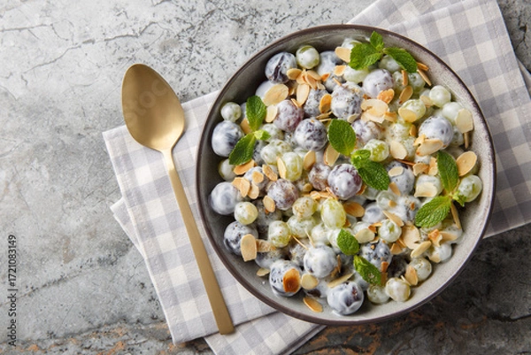 Obraz Fresh sweet Sultana grape salad with almond flakes, mint, Greek yogurt and cream cheese dressing close-up in a plate on the table. Horizontal top view from above