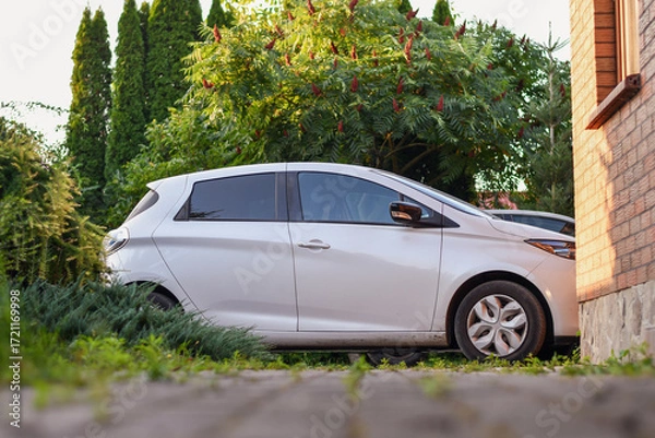 Fototapeta Detail of a car parked at garage on the background of garden. Selective focus.