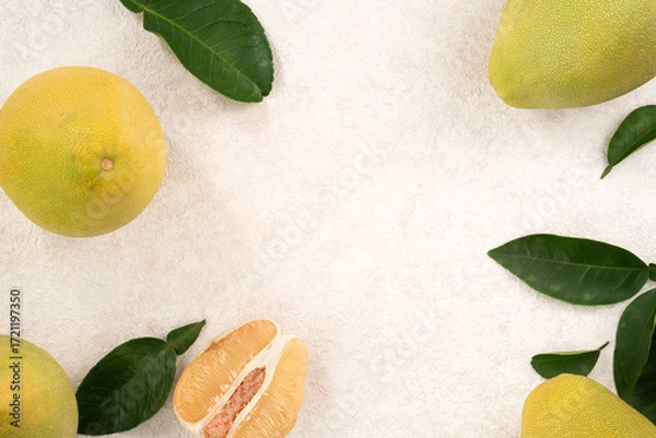 Obraz Fresh pomelo fruit with leaf on white table background.