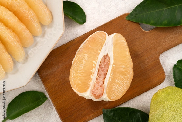 Obraz Fresh pomelo fruit with leaf on white table background.