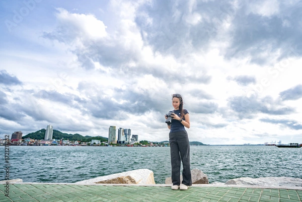 Fototapeta 바닷가 선착장을 배경으로  태국의 사진작가 미녀 모델이 촬영하면서 포즈를 취한 사진,
