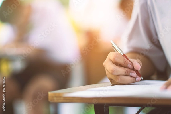 Fototapeta Closeup to hand of student  holding pen and taking exam in classroom with stress for education test .