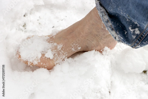 Fototapeta A closeup of a bare foot stepping in fresh snow