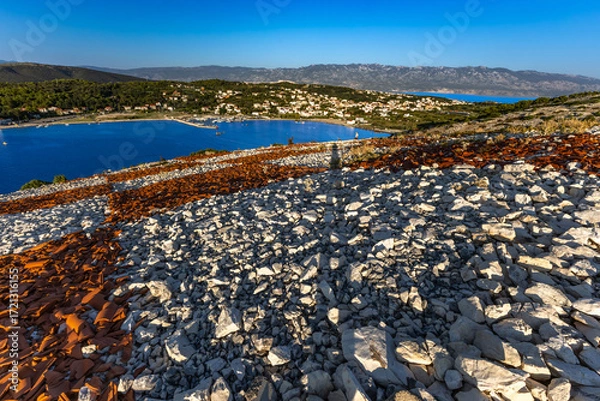 Fototapeta Rab the hill above the port in Lopar, the Croatian flag placed on a slope of red roof tiles,