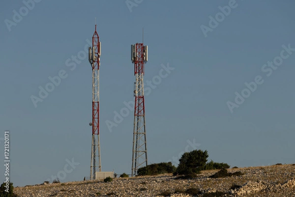 Fototapeta Telecommunication antenna masts for broadcasting television and radio signals on a hill above the town of Lopar on the island of Rab