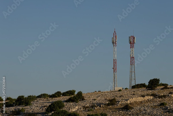 Fototapeta Telecommunication antenna masts for broadcasting television and radio signals on a hill above the town of Lopar on the island of Rab
