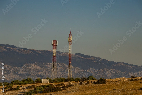 Fototapeta Telecommunication antenna masts for broadcasting television and radio signals on a hill above the town of Lopar on the island of Rab
