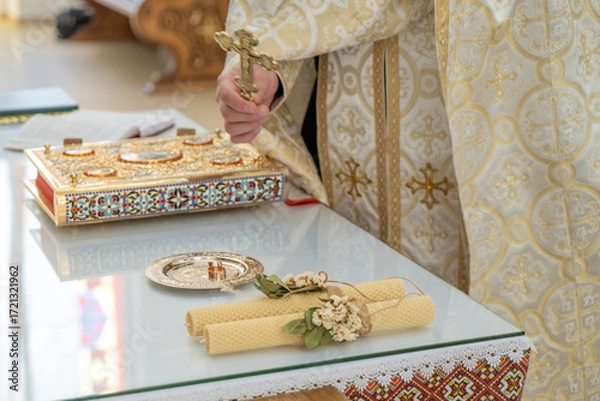 Fototapeta Wedding rings on a table with an open bible and candles