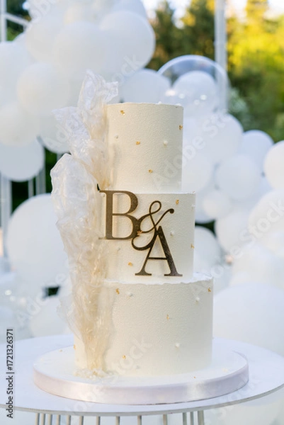 Fototapeta Wedding cake with letters B and A decorated with white balloons