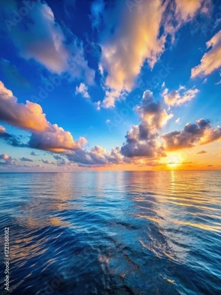 Fototapeta A serene ocean with a clear blue sky and white clouds drifting lazily across the horizon
