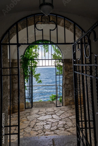 Fototapeta Arched gate with ivy overlooking tranquil blue sea and horizon, scenic coastal view Lungormare Opatija Croatia
