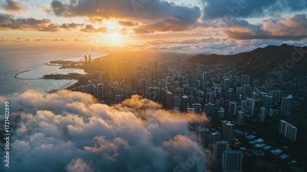 Fototapeta Aerial view of a vibrant sunset over a coastal city with clouds and mountains.