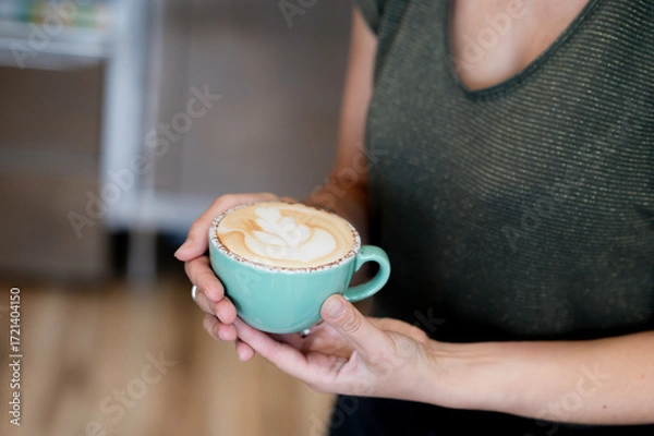 Fototapeta Barista holding a cup of latte with heart-shaped foam art