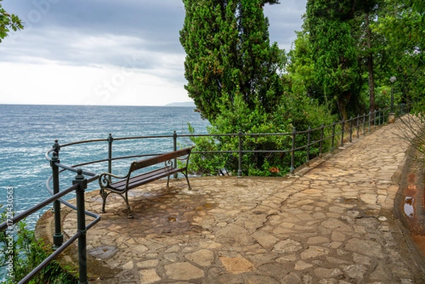 Fototapeta Stone seaside path with a bench Lungomare with railing along Adriatic coast in Opatija, Croatia
