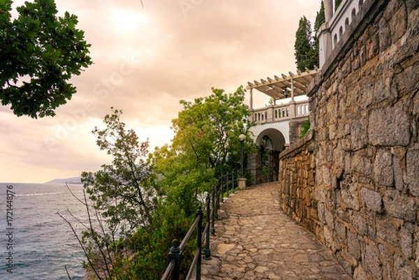 Fototapeta Scenic seaside stone path Lungomare with villa terrace at sunset on Adriatic coast