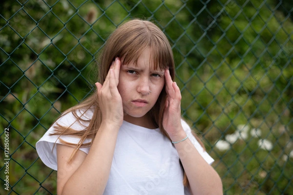 Fototapeta A girl got a headache while walking in the forest, probably because she spends too much time at home and rarely goes out into nature. Headache in teenage girl