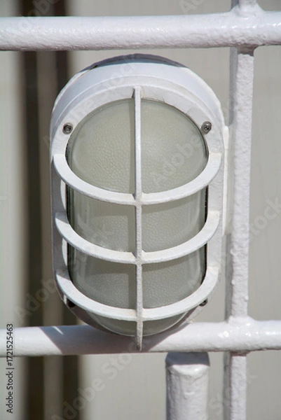 Fototapeta Close up of a marine bulkhead light fixture, with a protective grid cover. a classic detail of a ships safety and lighting equipment.