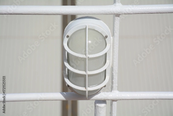 Fototapeta A retro style ships light fixture, with a robust and functional design, mounted on the railing. It symbolizes safety and night navigation.