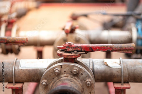 Fototapeta Handle controlling gate valve of water pumping unit which is used in oil field operation. Heavy industrial equipment object, close-up and selective focus at the valve handle.