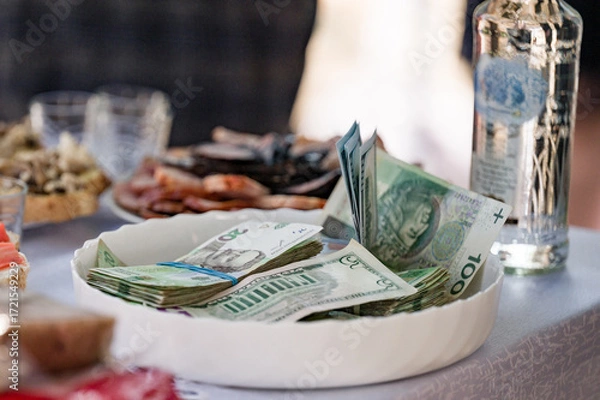 Fototapeta Cash and snacks on a table.  Money in a bowl, ready for a celebration or event.