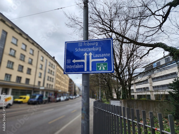 Fototapeta The sign for Bern goes straight to Fribourg, Schwarzenburg. The left arrow turns to Interlaken. The right arrow turns to Lausanne, Switzerland. Interesting tourist destinations in Europe.