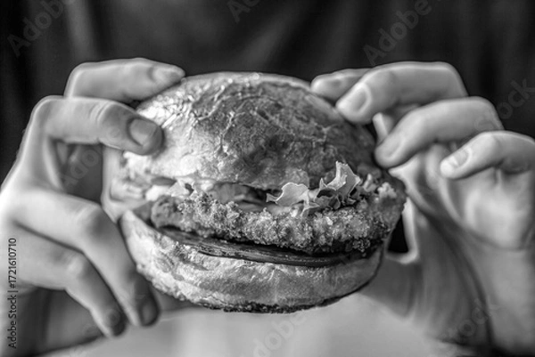 Fototapeta Man hands holding burger with meat, cheese and vegetables. Man holds burger with hands. Black and white