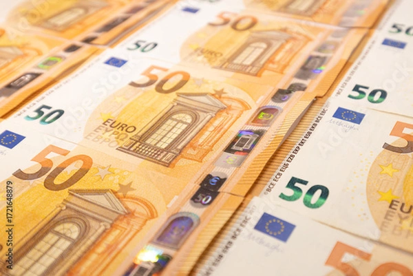 Fototapeta Close-up of multiple 50 euro banknotes spread out in rows, symbolizing wealth, finance, savings, investment, economy, and monetary value.