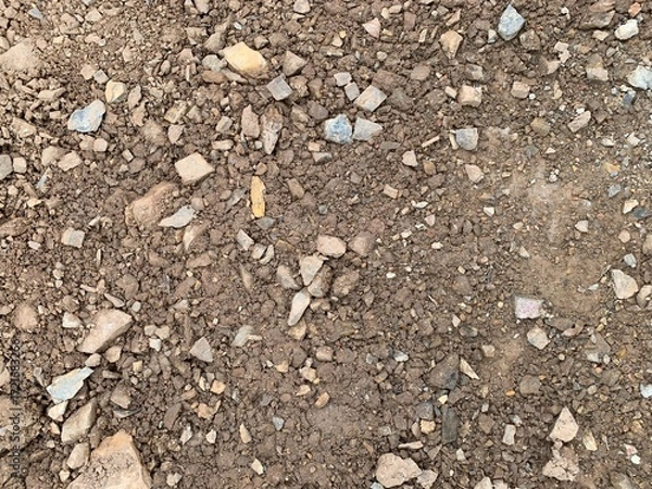 Fototapeta A high-angle, detailed shot of rough, broken earth mixed with small and medium-sized rocks and pebbles, creating a rich natural texture.