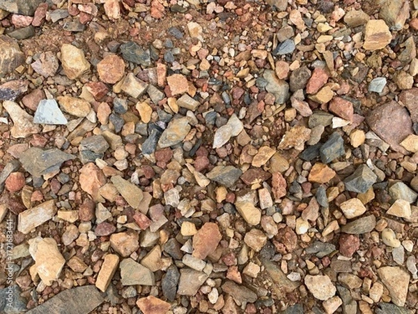 Fototapeta A high-angle, detailed shot of a vibrant mix of small, broken rocks and pebbles in various shades of red, brown, tan, and gray, creating a colorful and textured surface.