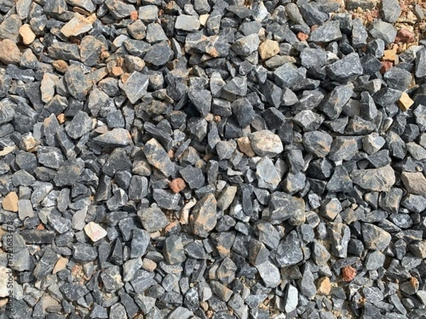 Fototapeta A high-angle, detailed shot of a dense pile of crushed gray stone and rock, with some hints of brown and red dirt, suitable for a construction or natural background.
