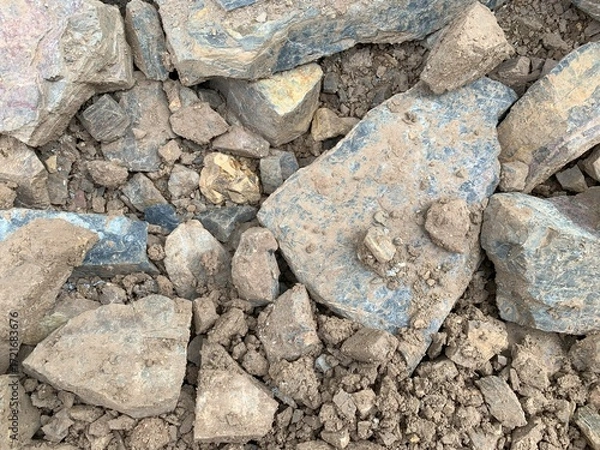 Fototapeta A high-angle, detailed shot of a pile of broken rocks and rubble, covered in patches of dry dirt and clay, creating a rough and natural texture.