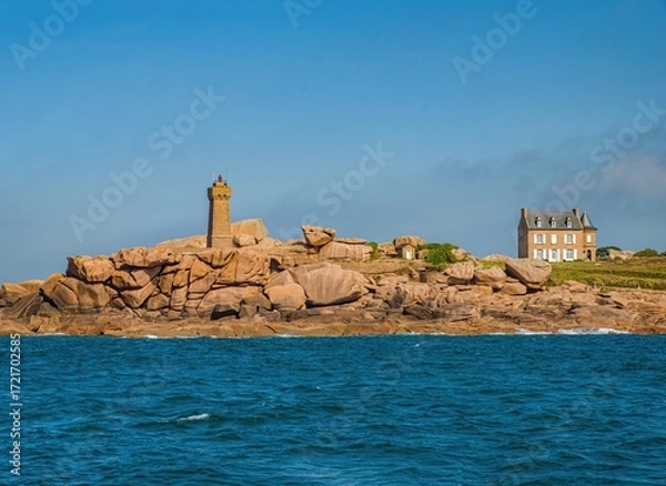Fototapeta Picturesque view of the famous Ploumanac'h lighthouse (Mean Ruz) on the Pink Granite Coast in Brittany, France. The rugged shoreline with unique rose-colored granite rocks, a traditional French house
