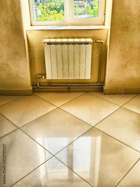 Fototapeta Bright corner of a room featuring polished tiles and a radiator with a window view of greenery outside